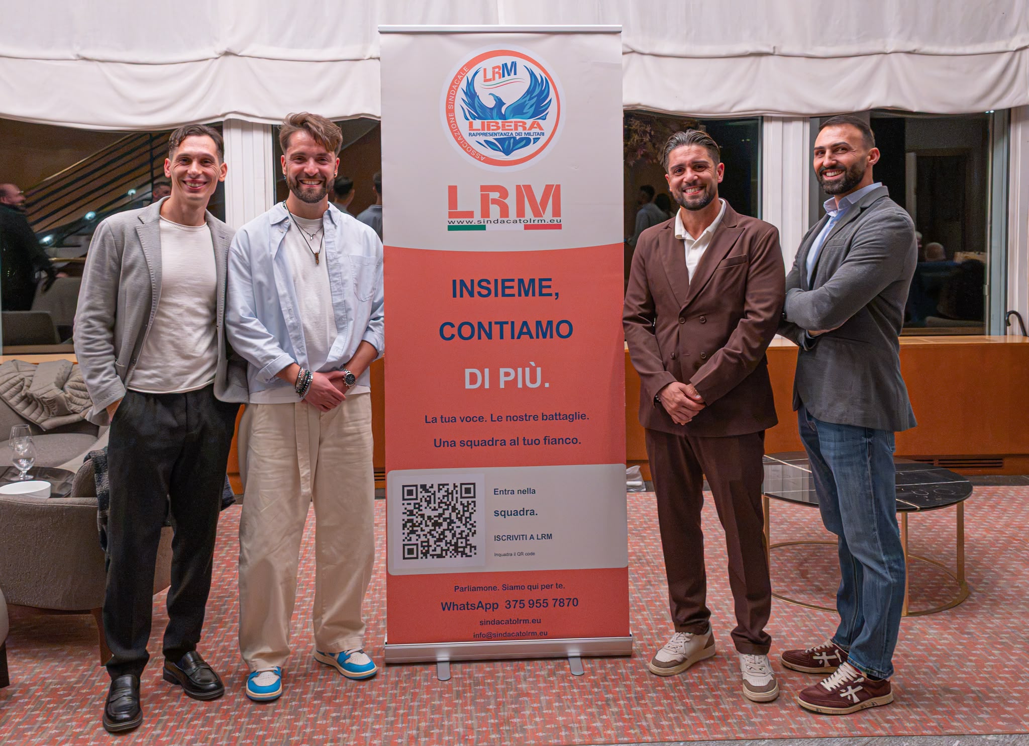 Quattro partecipanti accanto al roll-up LRM durante Via Emilia
